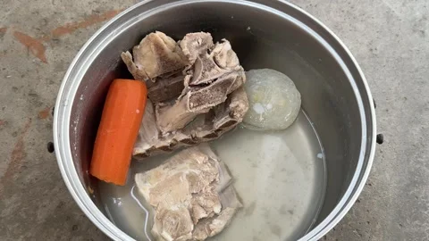 Boiled bones with carrot and onion in a metal pot of broth Stock Footage 341830164