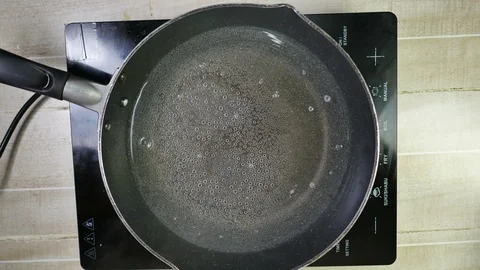 Boiled bubble fresh water with smoke in induction pan on electric stove Stock Footage 130052767