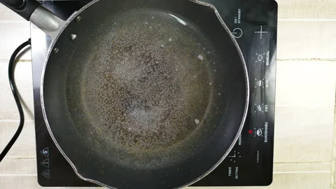 Boiled bubble water in black induction pan on electric stove Stock Footage 130595897