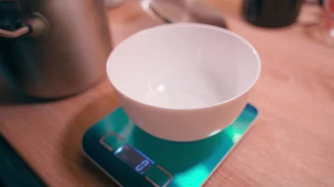 Boiled buckwheat is being poured into a white plate standing on kitchen scales Stock Footage 322170491