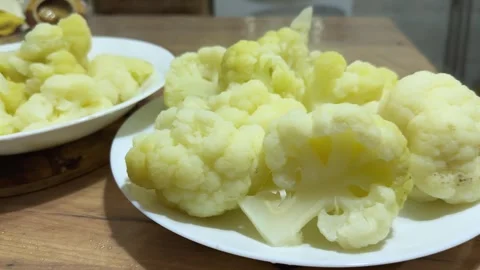 Boiled cauliflower pieces on two plates on table, front view Stock Footage 324967742