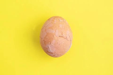 Boiled chicken egg cracked shell on a yellow background, top view. Stock-Fotos