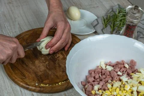 Boiled chicken egg is cut with kitchen knife on wooden cutting board and ch.. Stock Photos