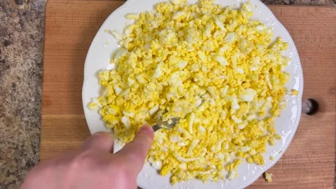 Boiled chicken egg halves with bright yolks are mashed with a fork in a plate. Video stock 301322192