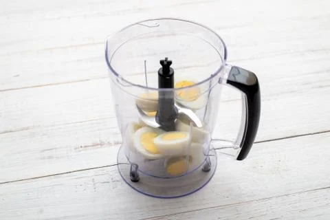 Boiled chicken eggs in a food processor, chopper on a light wooden background Stock Photos
