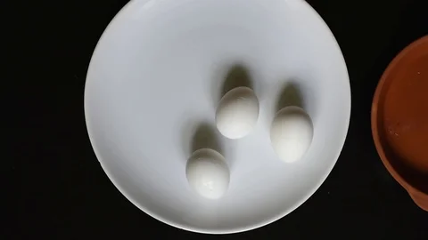 Boiled chicken eggs on a white plate on a black table background Stock Footage 96187341