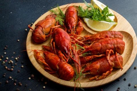 Boiled cooked crayfish crawfish ready to eat on wooden plate on black backgro Stock Photos