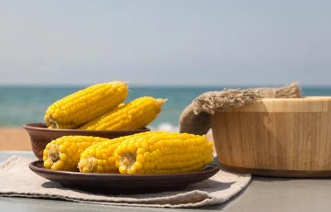 Boiled corn on the cob on an earthenware plate. fresh tomatoes and cucumbers in Stock Photos