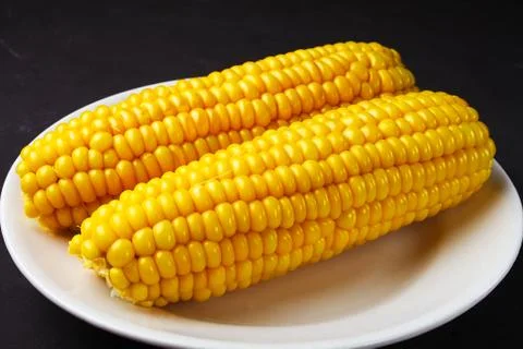 Boiled corn on a white plate, close-up Stock Photos