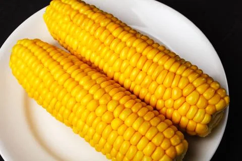 Boiled corn on a white plate, close-up, selective focus Stock Photos