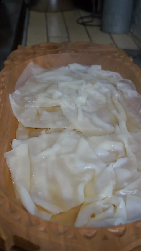 Boiled dough sheets for traditional beshbarmak placed in a carved wooden platter Видео 342627883