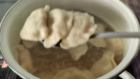 Boiled dumplings with potatoes are caught from a boiling pot Stock Footage 232219597