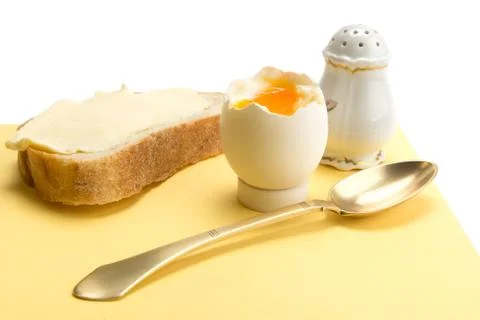 Boiled egg, bread with butter, salt cellar and brass spoon Stock Photos
