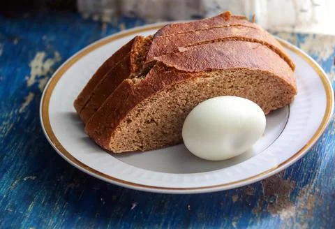 Boiled egg with bread on a plate, on a blue, old table. Foto stock