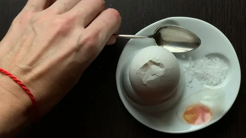 Boiled egg is broken by tapping a spoon on a dark background Stock Footage 103361894
