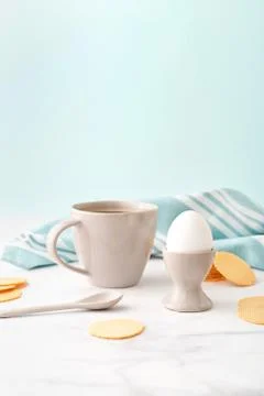 Boiled egg in ceramic egg cup, cup of coffee and thin crispy corn chips on ba Stock Photos