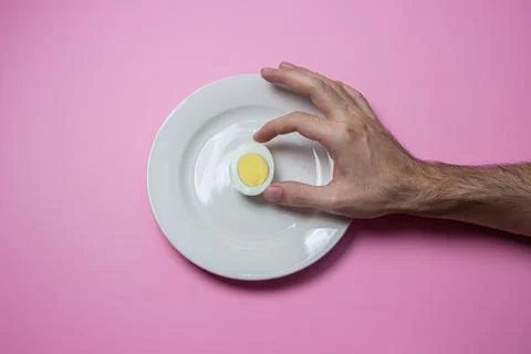 A boiled egg cut in half on a plate. The hand reaches for food. Healthy breakfas Stock Photos