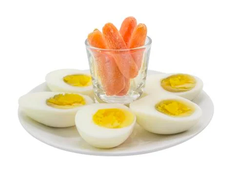 Boiled egg half cut snack with baby carrot on white plate Stock Photos