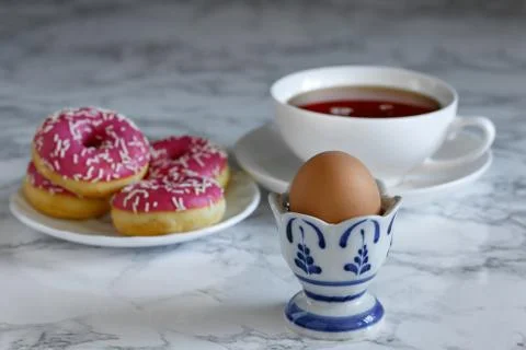 Boiled egg with tea and donuts in the background Stock Photos
