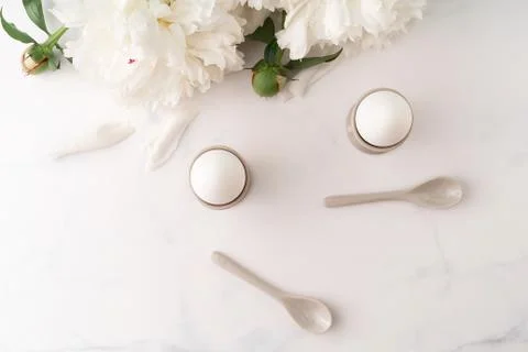 Boiled eggs in ceramic egg cups with ceramic spoons on marble table top Stock Photos