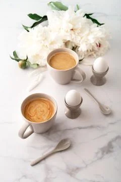 Boiled eggs in ceramic egg cups and two cups of coffee on background of beaut Stock Photos
