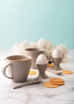Boiled eggs in ceramic egg cups and two cups of coffee on background of Stock Photos