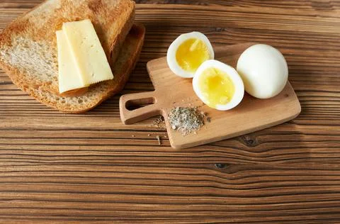 Boiled eggs, cheese and bread on wooden background. Top view Stock Photos