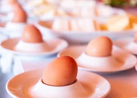 Boiled eggs served from white eggcups Stock Photos