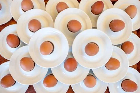 Boiled eggs served from white eggcups Stock Photos