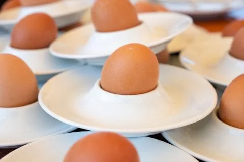 Boiled eggs served from white eggcups Stock Photos