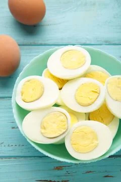 Boiled eggs in white ceramic plate on blue background. Stock Photos