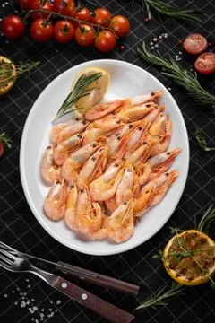 Boiled king prawns on a white plate. Decorated with a slice of lemon. Stock Photos