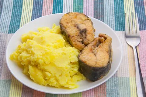 Boiled mashed potatoes on a plate with fried salmon on table Stock Photos