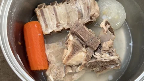 Boiled meat bones with whole carrot and onion in metal pot 스톡 동영상 343405917