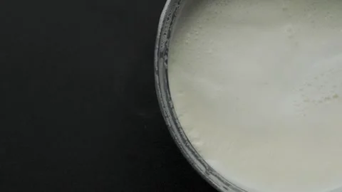Boiled milk pot entering frame on black background top down view Stock Footage 335911223