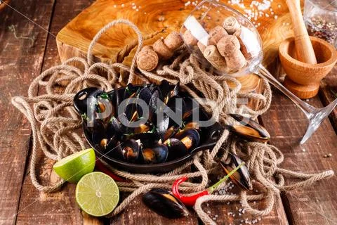 Boiled mussels in copper dish for cooking on wooden background Stock Photos