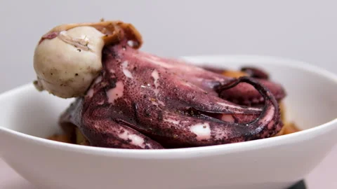 Boiled octopus on a white long plate swirls in front of the camera examine the Stock Footage 307487186