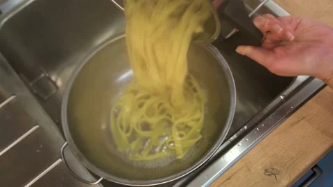 The boiled pasta is drained with water in a colander, making pasta Stock Footage 148552933