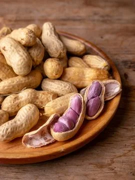 Boiled peanuts in shell with purple violet skin kernels revealed on wooden .. Stock Photos