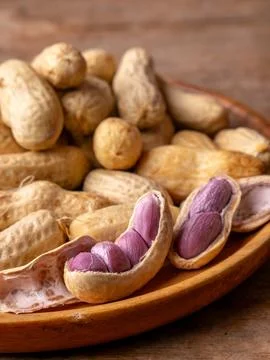 Boiled peanuts in shell with purple violet skin kernels revealed on wooden .. Stock Photos