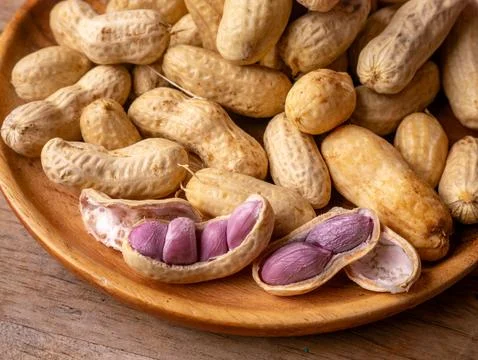 Boiled peanuts in shell with purple violet skin kernels revealed on wooden .. Stock Photos