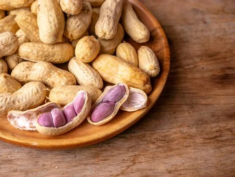Boiled peanuts in shell with purple violet skin kernels revealed on wooden .. Stock Photos