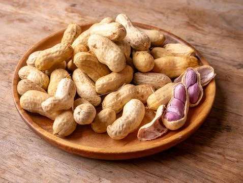 Boiled peanuts in shell with purple violet skin kernels revealed on wooden .. Stock Photos