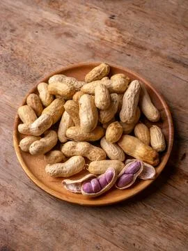 Boiled peanuts in shell with purple violet skin kernels revealed on wooden .. Stock Photos