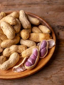 Boiled peanuts in shell with purple violet skin kernels revealed on wooden .. Stock Photos