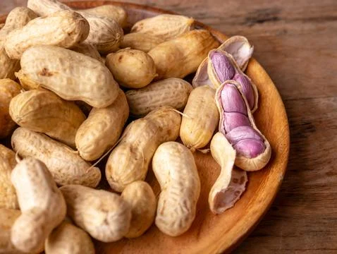 Boiled peanuts in shell with purple violet skin kernels revealed on wooden .. Stock Photos