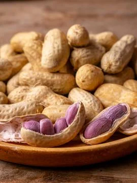 Boiled peanuts in shell with purple violet skin kernels revealed on wooden .. Stock Photos