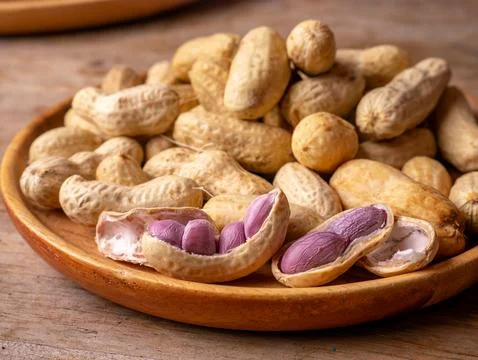 Boiled peanuts in shell with purple violet skin kernels revealed on wooden .. Stock Photos