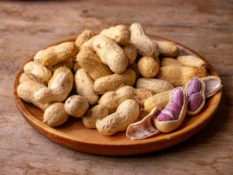 Boiled peanuts in shell with purple violet skin kernels revealed on wooden .. Stock Photos