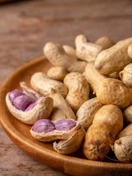 Boiled peanuts in shell with purple violet skin kernels revealed on wooden .. Stock Photos